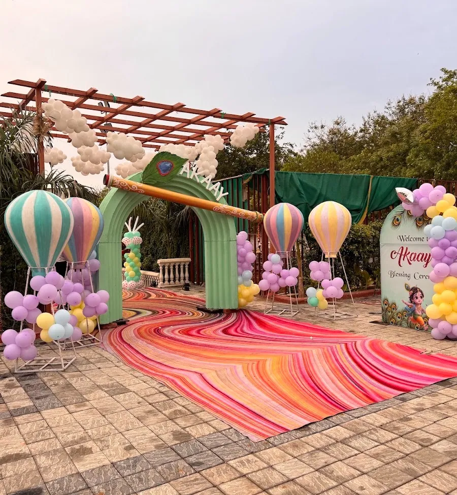 Pastel entrance arch for a baby blessing ceremony with hot-air-balloon decorations, cloud balloon garlands on the pergola and a rainbow fabric runner.