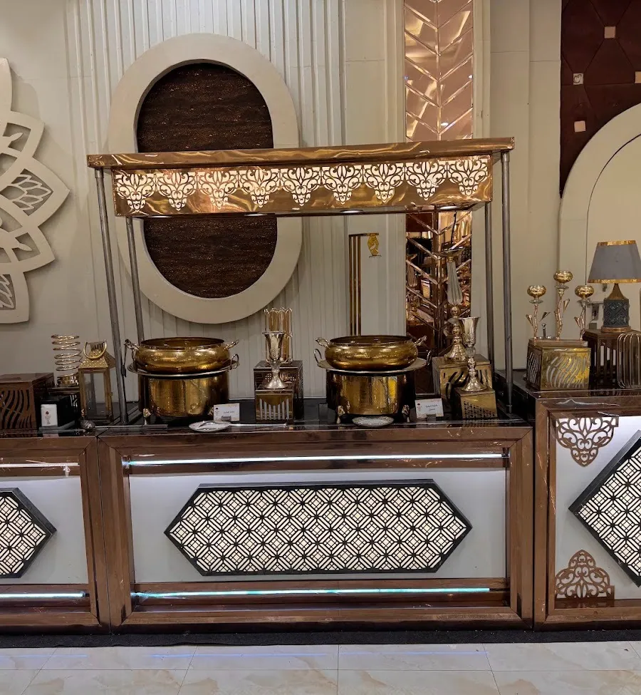 Indoor buffet counter in copper and rose-gold with illuminated hexagonal lattice panels, topped with hammered brass pots and silver serveware.