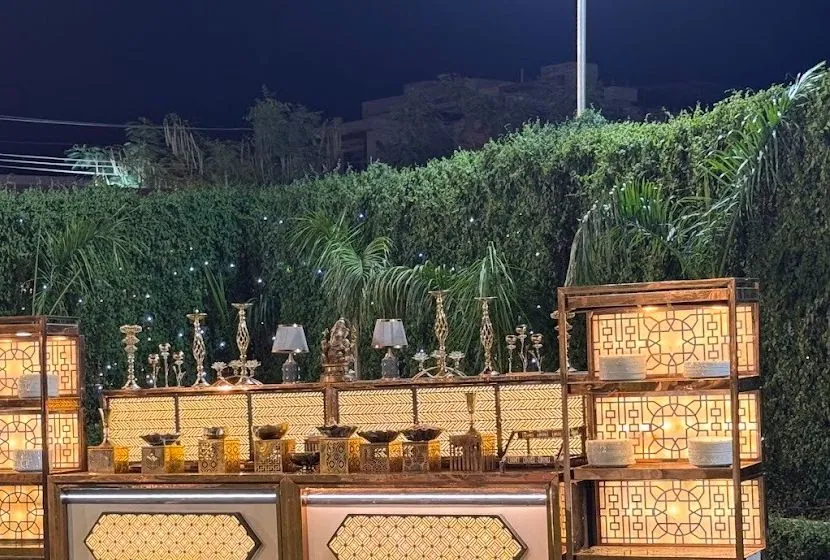 Madhavam's signature buffet counters on the lawn at night: backlit jaali lattice towers stacked with plates, brass chafing bowls and candelabra along the counter.